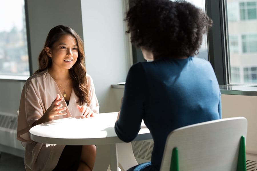 Deux femmes échangent autour d'une table dans un bureau